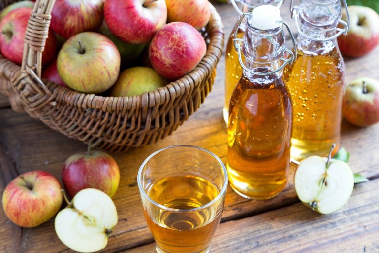 Ein Glas Apfelsaft, Apfelschorle in Flaschen und frische Äpfel