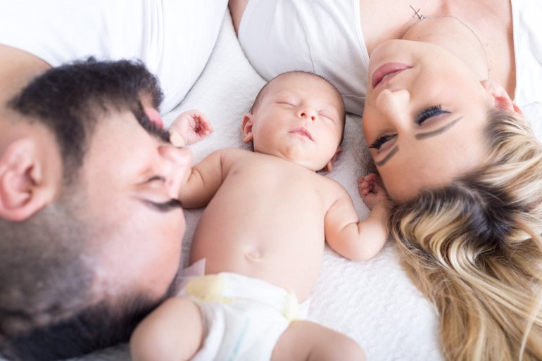 Co-Sleeping: Frau, Mann und Baby liegen im Bett