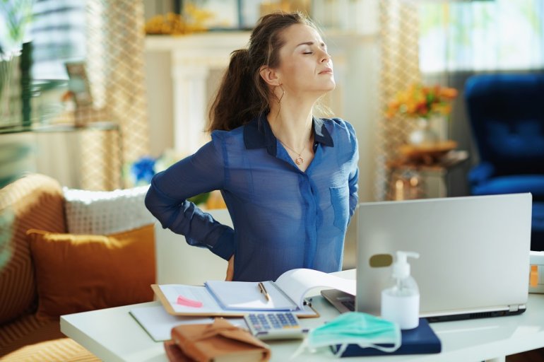 Frau mit Rückenschmerzen am Computer im Homeoffice