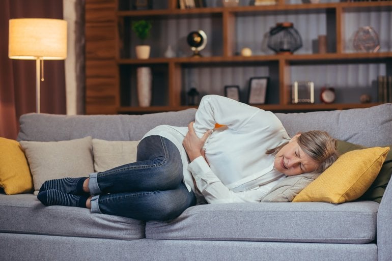 Frau mit Gallenkoliken liegt auf dem Sofa