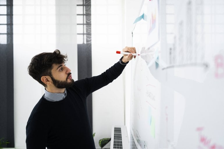 Linkshänder schreibt an ein Whiteboard