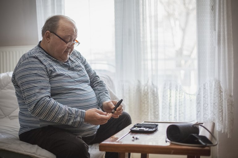 übergewichtiger Mann mit metabolischem Syndrom misst Blutzucker und Blutdruck