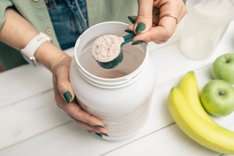 Frau bereitet sich einen Proteinshake zu