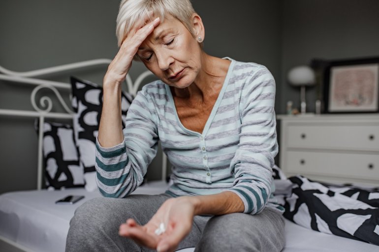 Frau nimmt Tabletten gegen Kopfschmerzen