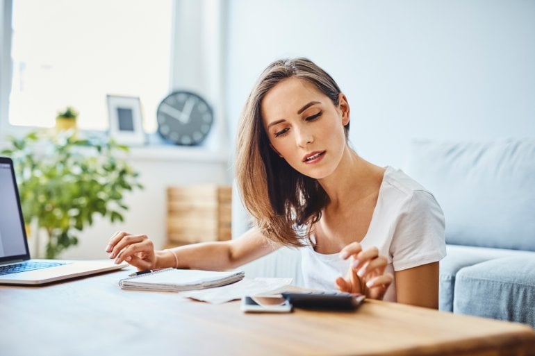 Frau mit Dyskalkulie arbeitet an Laptop und Taschenrechner