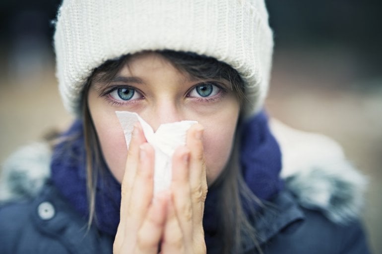 Frau mit Erkältung putzt Nase