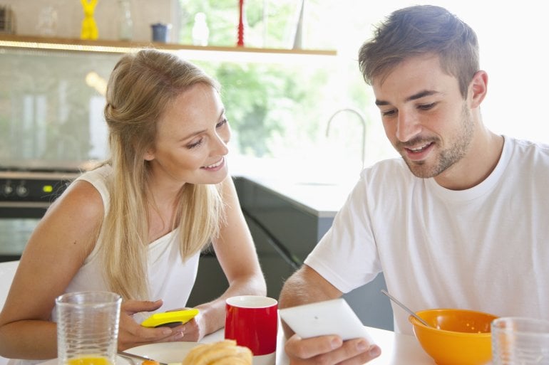 Pärchen nutzt Kalorienbedarfsrechner am Frühstückstisch